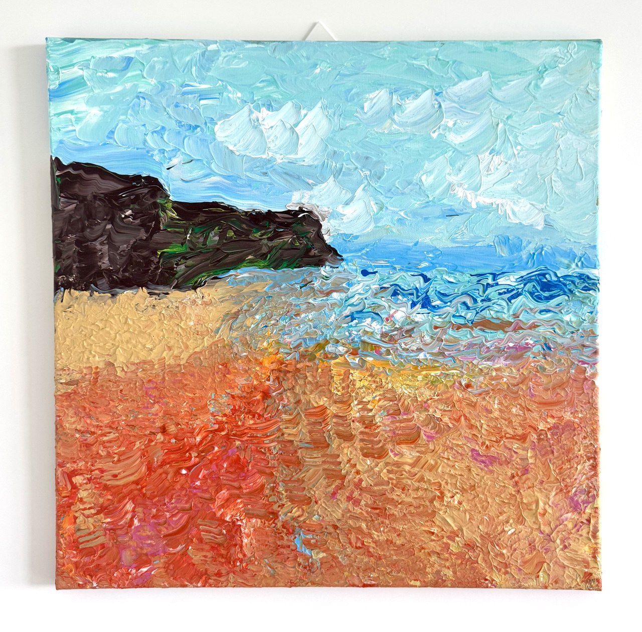 A textured seascape: pale blue sky, a dark rocky headland, blue water, and warm sand in thick, expressive strokes.